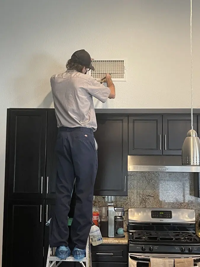 Technician inspecting an air vent during HVAC service in Effingham